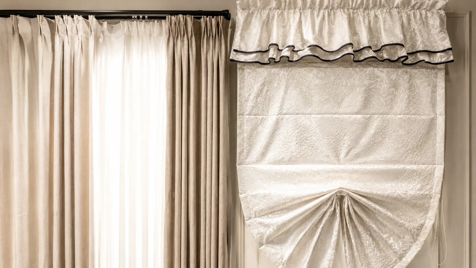 Curtains displayed beside a Roman blind