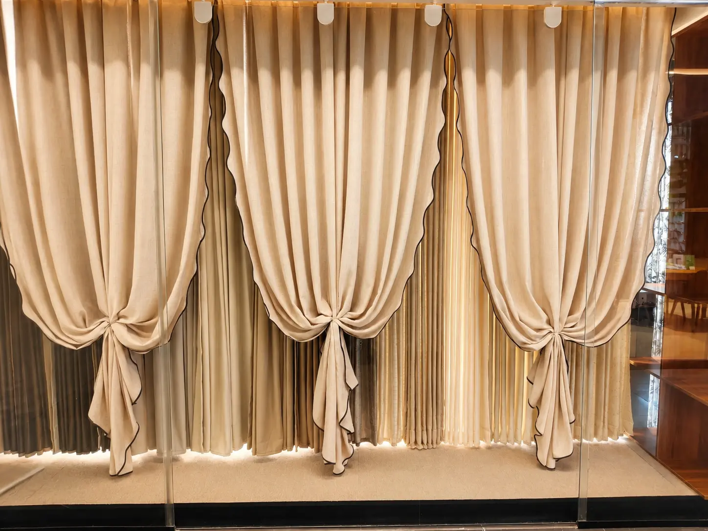 Cream curtain display with decorative swags and full height folds